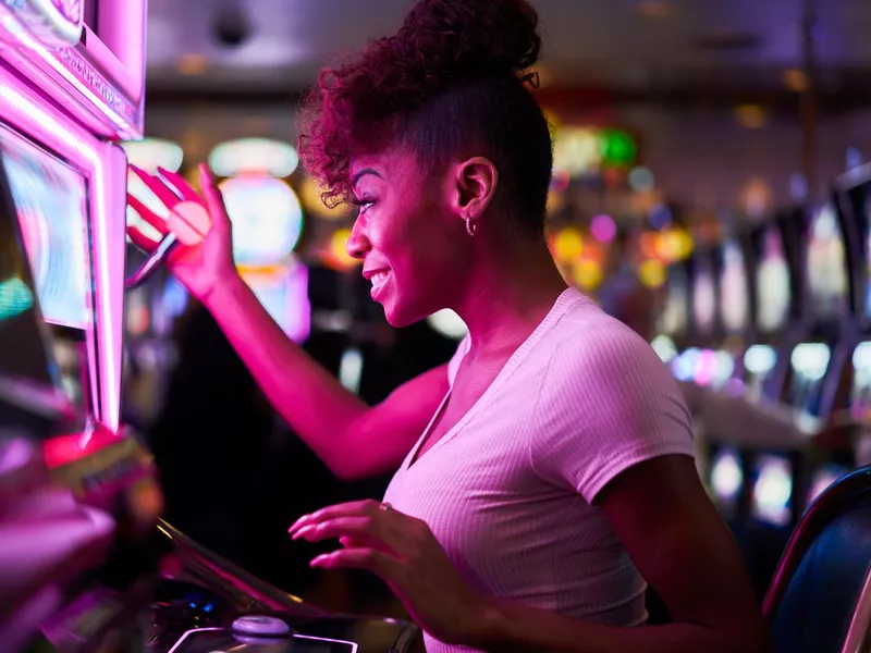 Happy woman gambling at casino playing slot machine